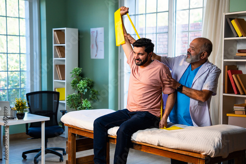 Indian physiotherapist teaching patient resistance band exercises for shoulder strength training