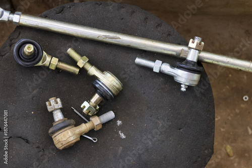 Steering rack tie rod end part lying on dark dirty surface at car garage for repair and replacement show shiny metal detail waiting for mechanic work to fix vehicle suspension system problem