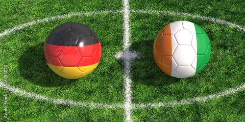 Konstfotografi Soccer balls with Germany and Ivory Coast flags on green grass football pitch