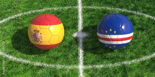 Soccer balls with Spain and Cape Verde flags on green grass football pitch