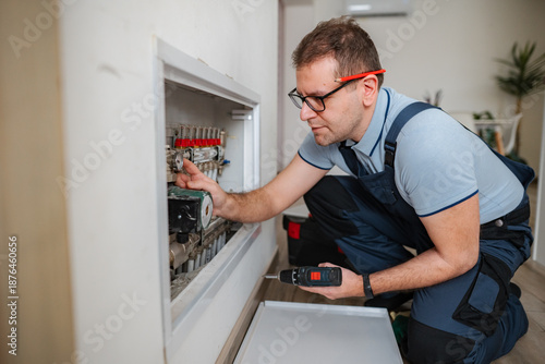 Wallpaper Mural Adult man repairing underfloor heating system at home Torontodigital.ca