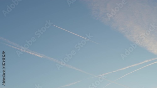 Sunset sky with multiple contrails of airplanes in summer