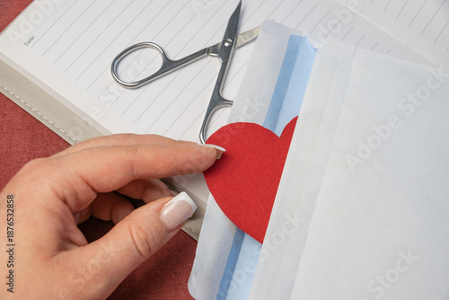Woman put a red paper heart into the envelope
