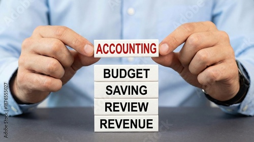 Professional hands hold an accounting block over budget saving and revenue concepts on a d