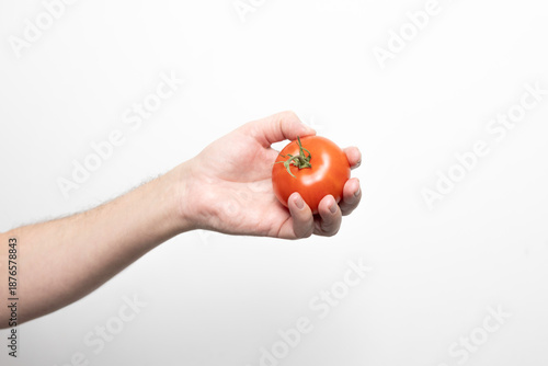 Męska dłoń trzymająca czerwonego pomidora