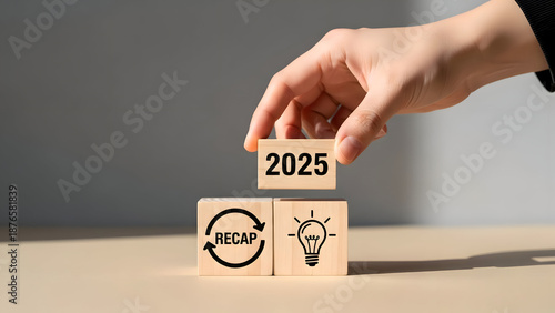 Hand placing 2025 block on recap and lightbulb blocks for new year planning image photo