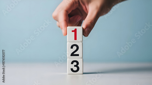 Hand stacking wooden blocks with numbers 123 in ascending order counting sequence