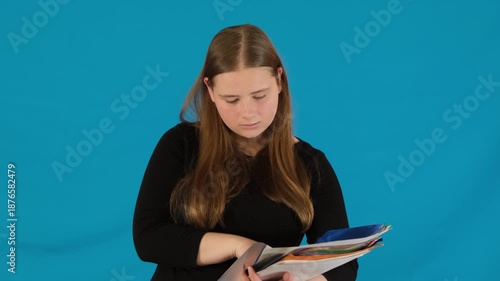 Young woman with long hair studies information in detail while holding many folders. Lady face changes from surprise to understanding