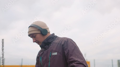Wallpaper Mural young white male dribbling basketball outdoors, closeup frames show focused expression, headphones and beanie, winter jacket zipped, cloudy sky backdrop, sequence includes bounce, drive, layup Torontodigital.ca