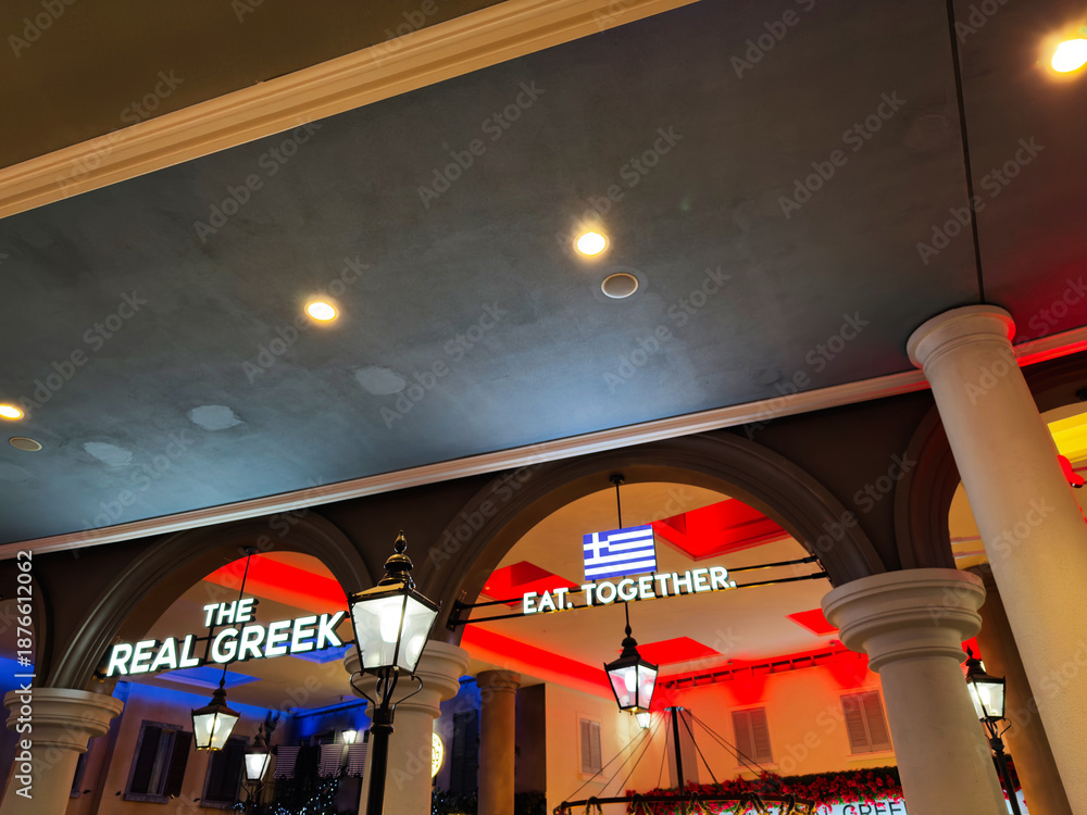 Fototapeta premium The Real Greek Eat Together signage under arches at Manchester UK restaurant, illuminated at night