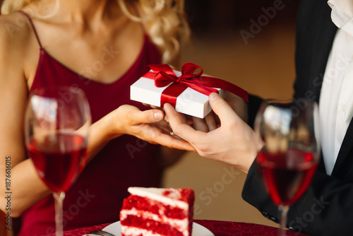 Canvas Print Beautiful woman and man sit together at table, giving each other gifts in cozy cafe