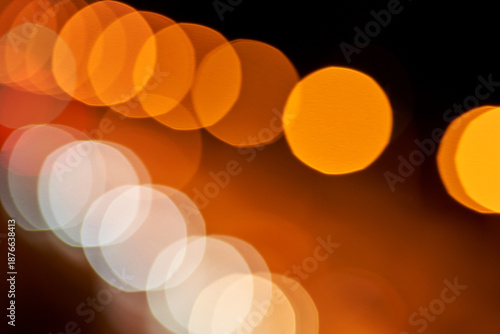 Abstract orange and white circular bokeh lights on black background.
