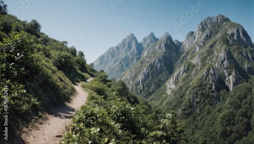 Hiking path winds through lush, green mountain terrain towards jagged peaks