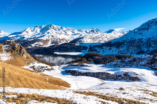Panoramic view of the Engadine, Lake Sils, and the village of Grevasalvas in winter.
