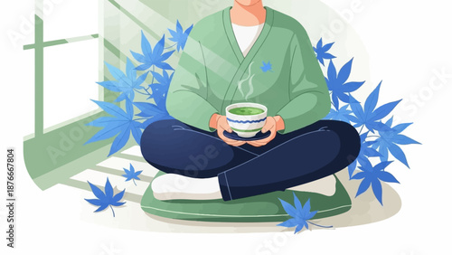Person in green cardigan sits cross-legged, holding a steaming cup of matcha near a window