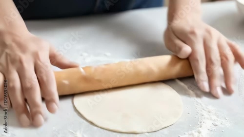 Hands using a wooden rolling pin to make dumpling skins