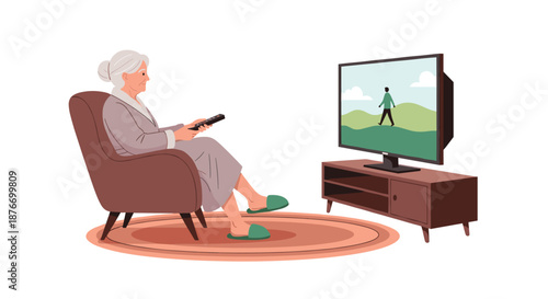 Elderly woman in a robe sitting comfortably in an armchair and using a remote control to watch television in her living room.