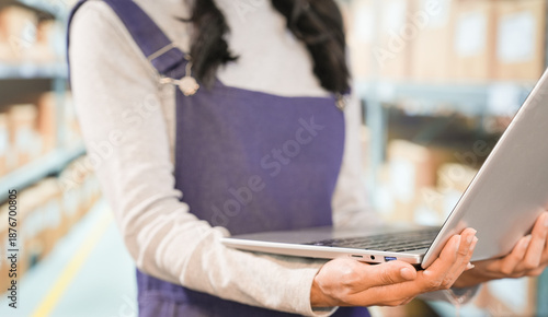 Canvas Print A young Asian woman, an auditor or intern, is verifying inventory using a digital tablet