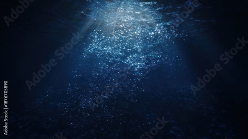 Submerged view with water bubbles rising. Shafts of light filtering down. Dark blue hues dominate