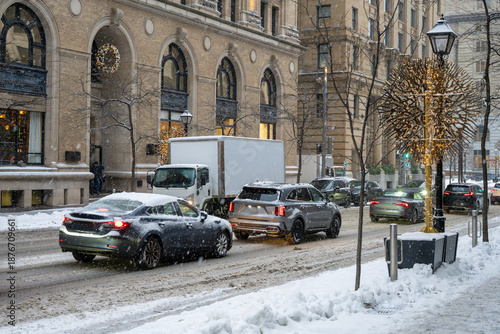 Winter traffic scene in a snowy street in Old Montreal during a snowfall covering roads and vehicles