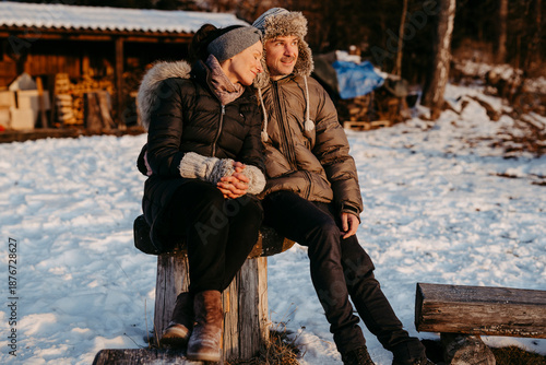 Glückliches, Paar sitzt auf Holzstamm im Schnee