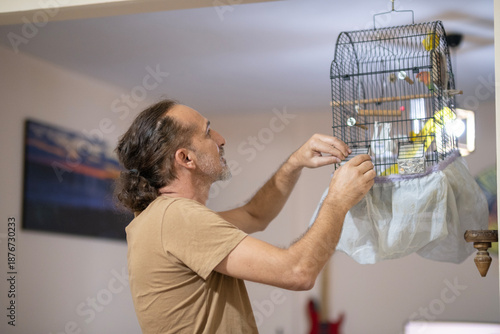 Man Feeding and Caring for Pet Birds. Bird Care and Daily Routine at Home. Man Taking Care of Pet Birds at Home. 