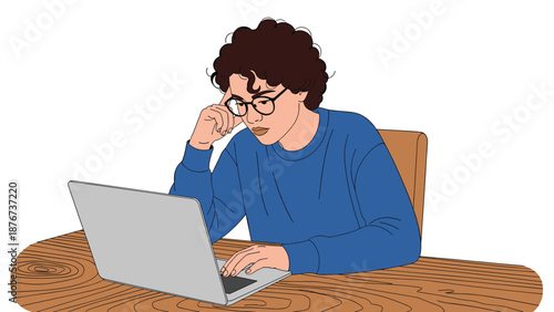 Focused young woman with glasses works or studies intently on a silver laptop while sitting at a rustic wooden table.