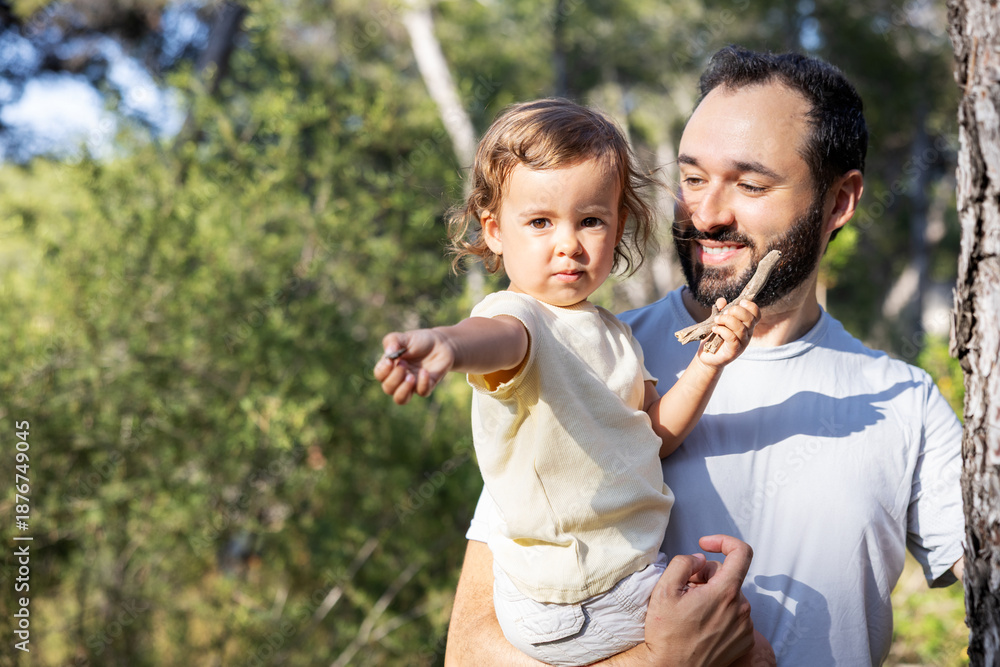 Obraz premium Little girl holding a stone while being carried by her father in the forest