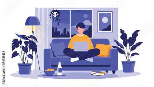 Young man sitting cross-legged on a sofa and working on his laptop in a cozy living room at night with city lights visible.