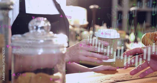 Handing paper takeaway cup between people wearing dark top at wooden counter with glass jar, charts