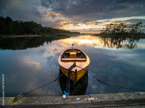 Tableau sur toile Schönes Holzboot am Steg bei Sonnenuntergang in Südschweden