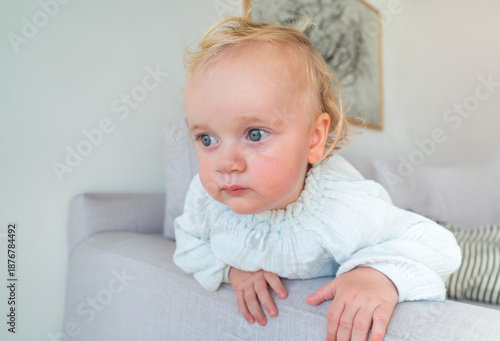 A baby is laying on a couch and looking at the camera