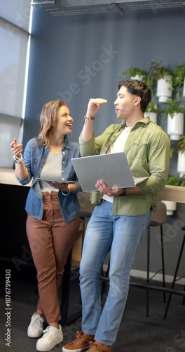 Vertical video: Diverse coworkers presenting idea on tablet in lounge then reviewing laptop screen