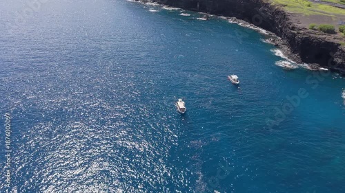 Aerial drone footage featuring a smooth orbit shot around a diving boat near the coastline in Reunion Island, with divers visible from a distance. Ideal for marine activity visuals