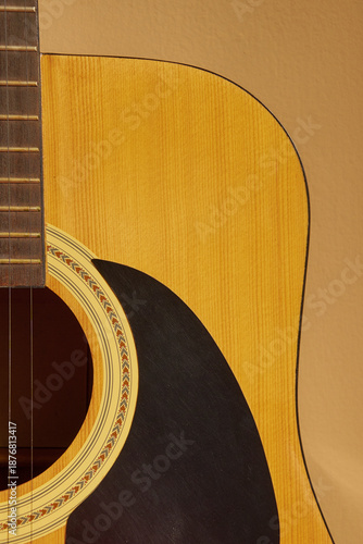 Close-up of acoustic guitar body and strings on a beige background with copy space