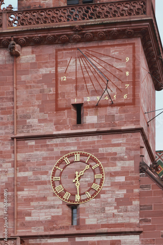Mechanical clock and sundial on cathedral tower. Basel, Switzerland