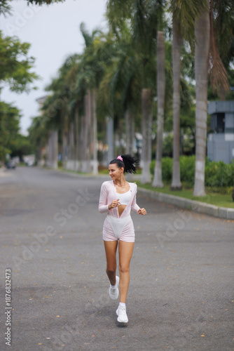 Quadro su tela Fit Young Woman Jogging Outdoors In Stylish Activewear On Tropical Path