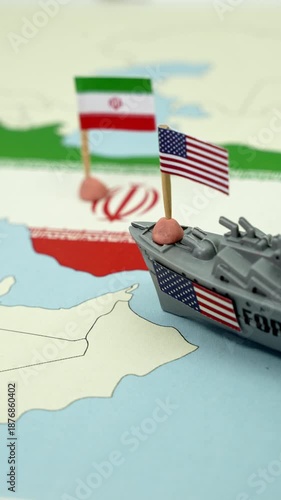 Conceptual representation of the geopolitical conflict between the United States and Iran, showing a toy warship with an American flag sailing towards a map of the Iranian coast