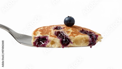Spatula holding blueberry pancake slice with juicy blueberries on white background for breakfast and dessert concepts