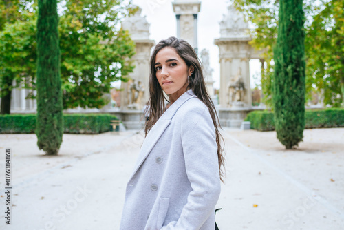 Woman walking in El Retiro Park in Madrid posing with white coat