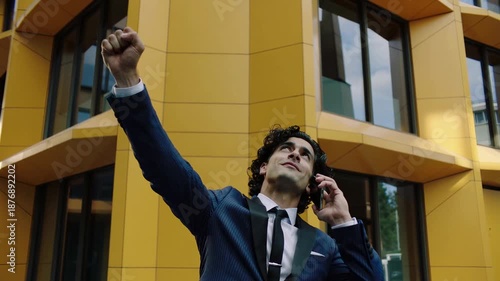 Excitement and celebration in a vibrant city as a man receives great news on a sunny day