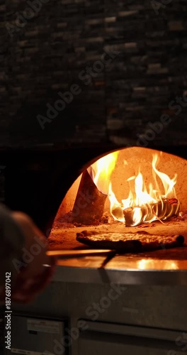 Wood-fired pizza oven burns brightly, heating the dark, rustic interior. Authentic Italian cooking and traditional cuisine concept. Warm culinary atmosphere.