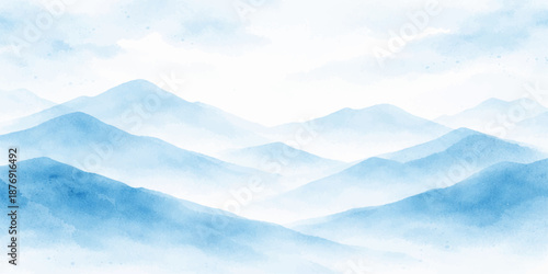 A beautiful aerial view of white clouds in the blue sky over a snowy mountain landscape with misty hills at sunset