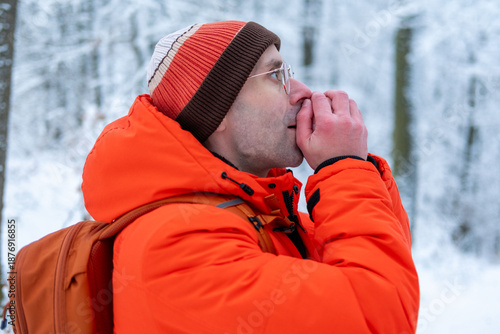 Obraz na płótnie young man freezing in winter forest, wearing hat and jacket, lost and vulnerable