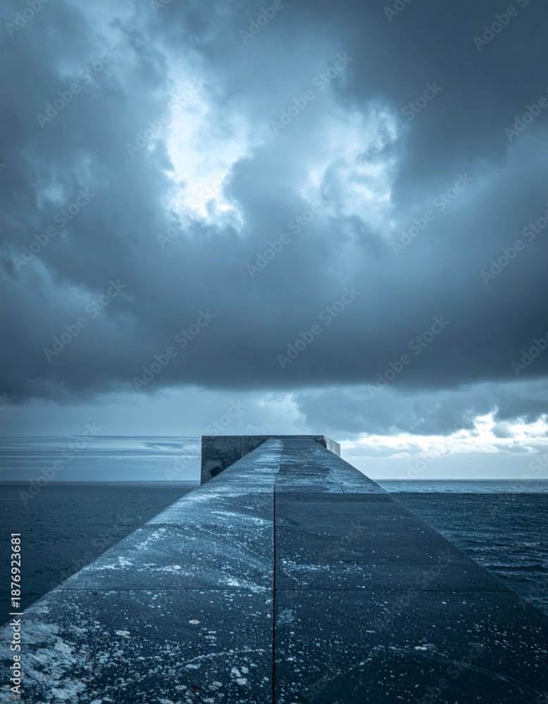 Fototapeta premium Concrete Pier Under Overcast Skies and Ocean Waves in Somber Tone