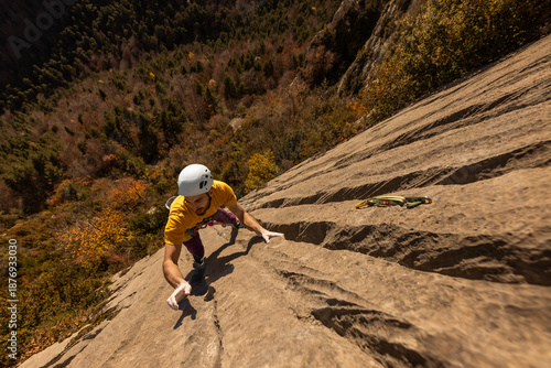 A man is climbing a rock wall with a yellow shirt