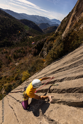 A man is climbing a rock wall with a rope