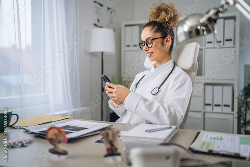 Wallpaper Mural Female doctor smiling and checking phone in medical office Torontodigital.ca