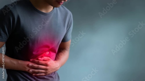 high-resolution medical-themed photograph showing a man wearing a gray T-shirt, bending slightly forward and holding his abdomen with both hands, indicating discomfort or abdomin 4K