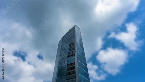 Timelapse of clouds moving behind a tall modern tower